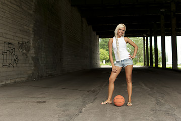 Image showing Beautiful blonde girl standing with basketball in the street