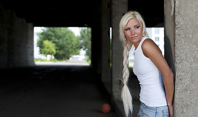 Image showing athletic girl in denim shorts and white T-shirt standing at the pillar