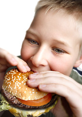 Image showing Young boy eating cheeseburger