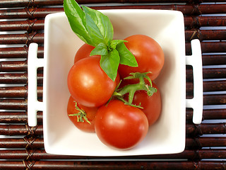 Image showing Small tomatoes with a leaf of basil