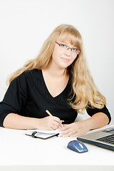 Image showing girl with a laptop writes in a notebook