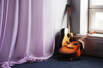 Image showing two acoustic guitar next the window
