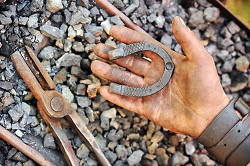 Image showing Detail of dirty hand holding horseshoe - blacksmith