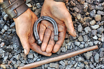 Image showing Detail of dirty hands holding horseshoe - blacksmith