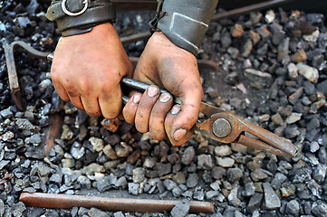 Image showing Detail of dirty hands holding pliers - blacksmith