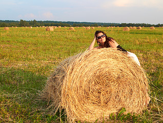 Image showing Girl near roll of hay.