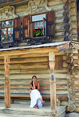 Image showing Young woman in front of Old Russian wooden house