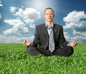 Image showing businessman in lotus pose in green grass