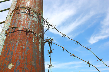 Image showing barbed wire on the pole against the blue sky