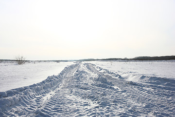 Image showing Snow covered road in winter with mountains in the distance