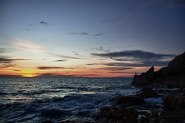 Image showing Sunset, rocks and fisherman on sea