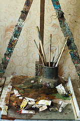 Image showing Easel for painting, tubes of oil paint and brushes