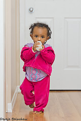 Image showing A cute baby girl walking with her bottle