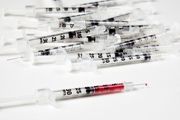 Image showing Pile of used syringes with a single filled one