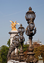 Image showing Ornate lamps lead the eye toward golden statue