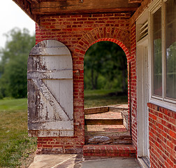 Image showing Open wooden door in brick wall to garden