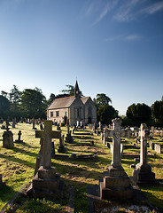 Image showing Sidelit view of graveyard with old church in the distance