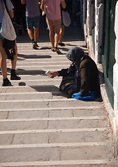 Image showing Old begging lady on steps