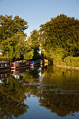 Image showing Canal barges reflected in calm water disturbed by ducks