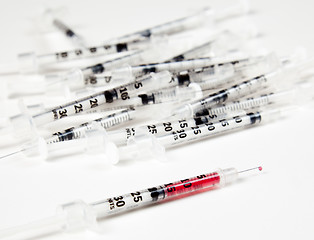 Image showing Pile of used syringes with a single one with fluid