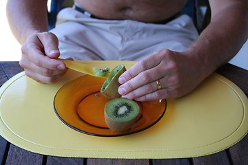 Image showing Man eating kiwi