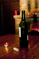 Image showing Wine bottle standing on table before fireplace