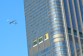 Image showing airplane fly over the modern building