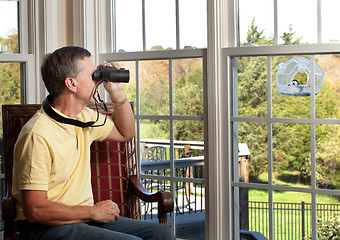 Image showing Man watching bird on feeder