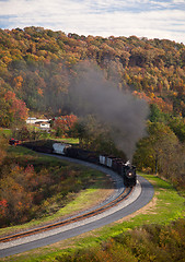 Image showing Steam train powers along railway