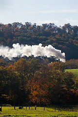 Image showing Steam train powers along railway