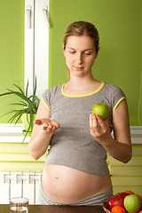 Image showing pregnant woman choosing between pills and apple