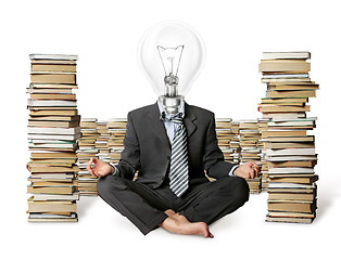 Image showing businessman in lotus pose and lamp-head with many books near