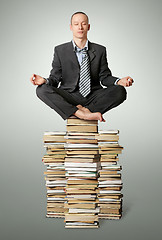 Image showing businessman in lotus pose with many books near