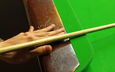 Image showing Young man concentrating while aiming at pool ball while playing 