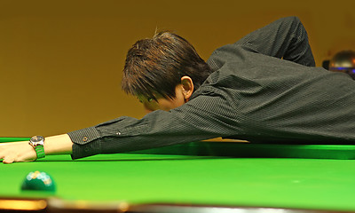 Image showing Young man concentrating while aiming at pool ball while playing 