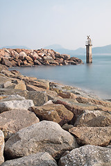 Image showing Lighthouse on a Rocky Breakwall: A small lighthouse warns of a r