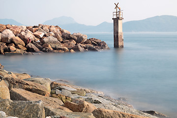 Image showing Lighthouse on a Rocky Breakwall: A small lighthouse warns of a r