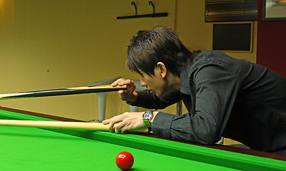 Image showing Young man concentrating while aiming at pool ball while playing 