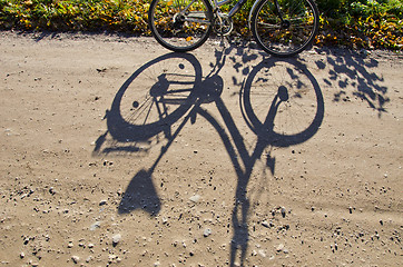 Image showing Standing bicycle shadow on gravel road.