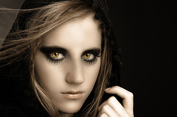 Image showing An attractive beautiful girl in hood against black background