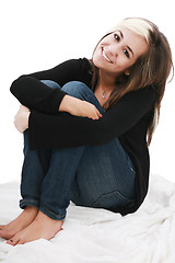 Image showing attractive teenage girl sits twining arms about legs 