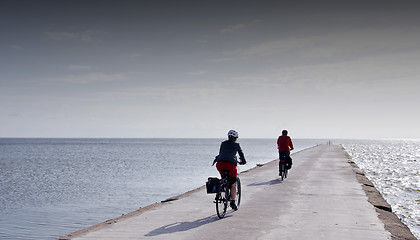 Image showing Cyclists ride on concrete pier in Curonian Lagoon.