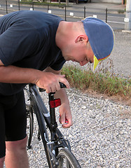 Image showing Cyclist adjusting the saddle