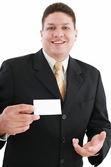 Image showing young attractive businessman shows his business card, focus in m