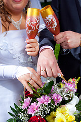 Image showing hands of brid and groom with bouquet and glasses of champagne