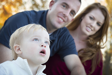 Image showing Cute Child Looks Up to Sky as Young Parents Smile