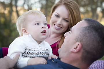 Image showing Cute Child Looks Up to Sky as Young Parents Smile