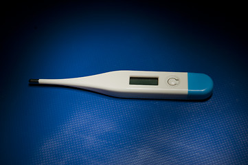 Image showing Isolated thermometer laying on blue studio table