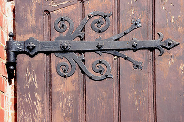 Image showing Detail of decorative hinges holding wooden door.