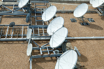 Image showing Collection of Large Satellite Dishes on Flat Gravel Roof